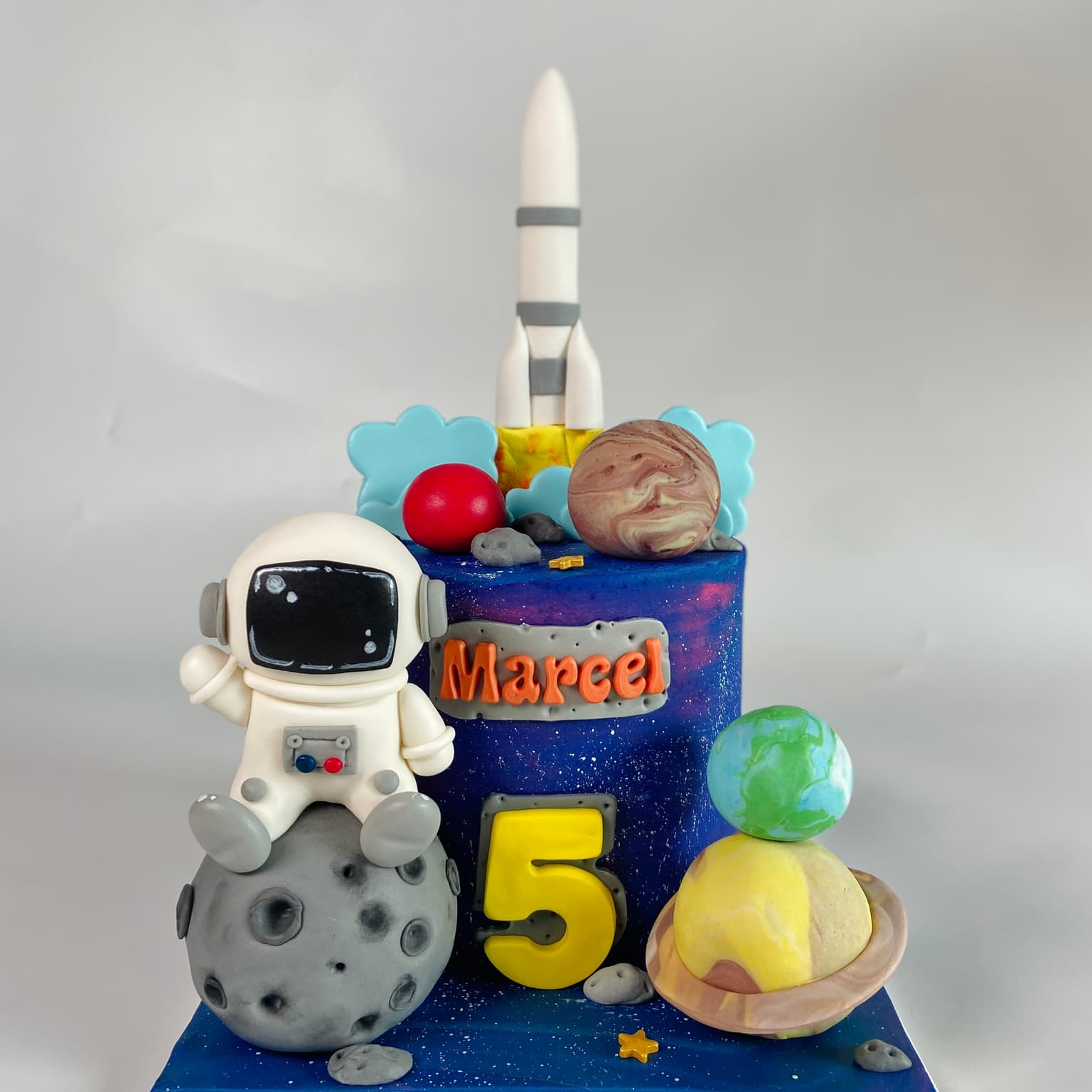 100% edible fondant sculpted astronaught sitting on the moon with rocket and planets scene