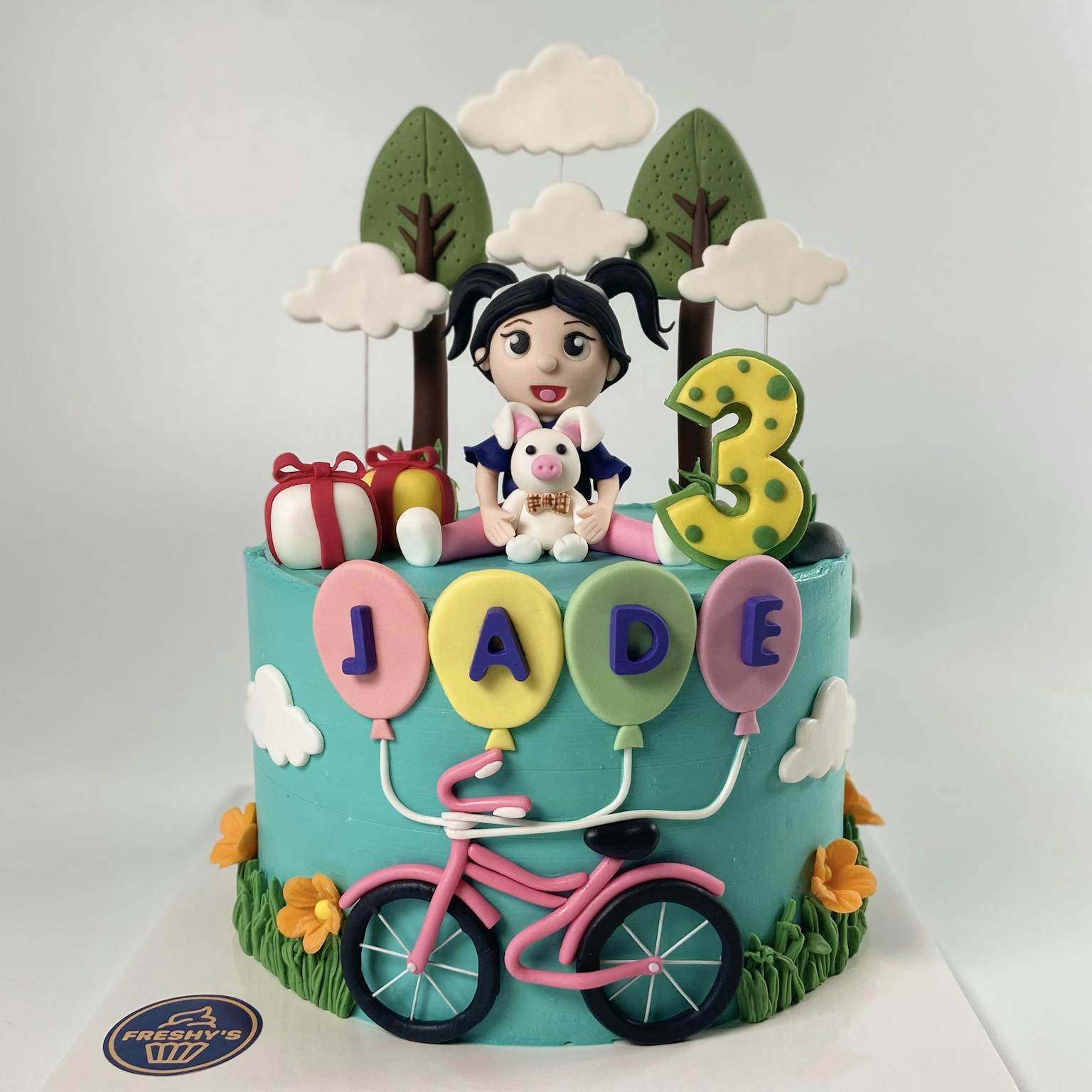100% edible fondant sculpted girls birthday cake with trees, clouds toys and a bicycle